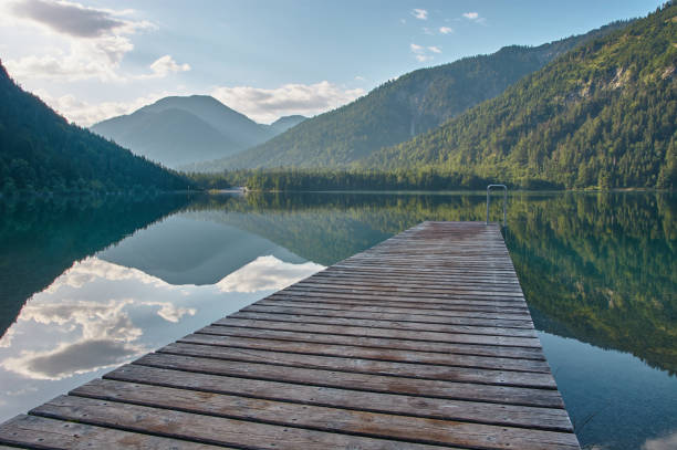 Dock leading into a mirroring mountain lake. Jetty leading into a beautiful mountain lake in the Austrian alps. jetty stock pictures, royalty-free photos & images