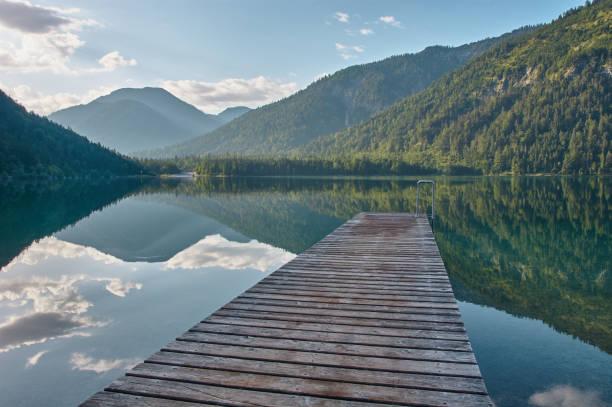 istock Dock leading into a mirroring mountain lake. 1334434539