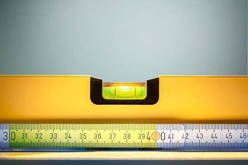 Orange bubble level or spirit level on a wooden shelf on the wall