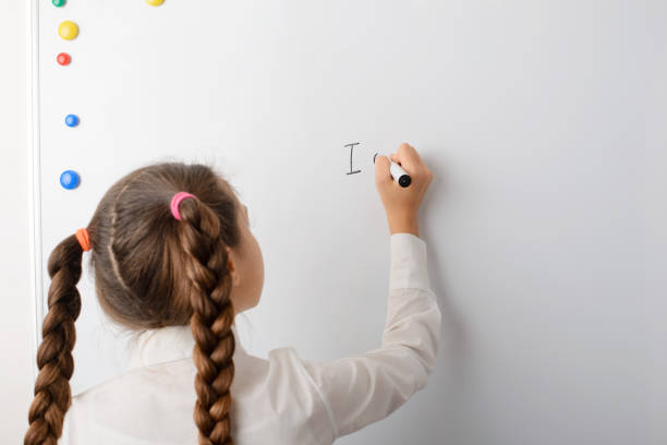 istock Cute little school writing words on the board during English lesson 1334435557