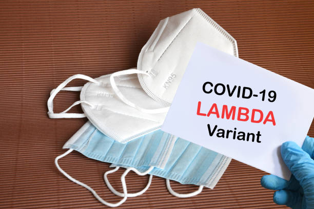 istock Doctor's hand in blue glove with white paper and text Covid-19 Lambda + Variant with various protection masks on background. COVID-19 lambda variant strain protection concept. 1334435901