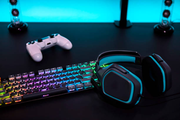 istock Various color backlighted gaming accessories on grey desk. Cyan illuminated wall. 1334435934