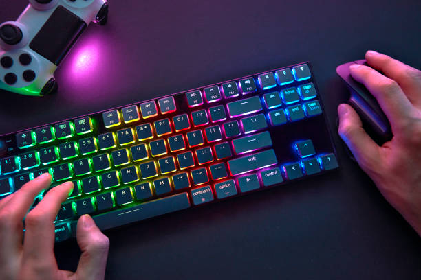 istock Close-up of male hands using color backlighted keyboard and mouse. 1334436067