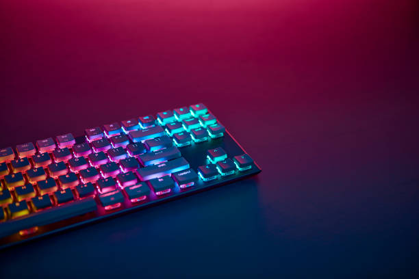 istock Rainbow color backlighted gaming keyboard on desk. Purple light from top. 1334436174