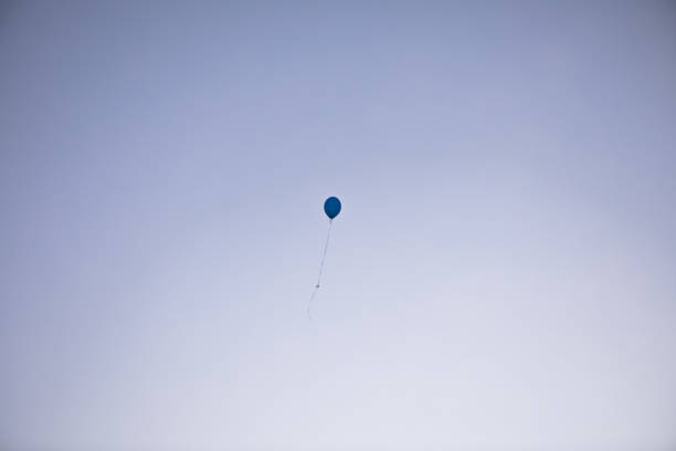 istock one blue balloon filled with helium against the blue sky. 1334437190