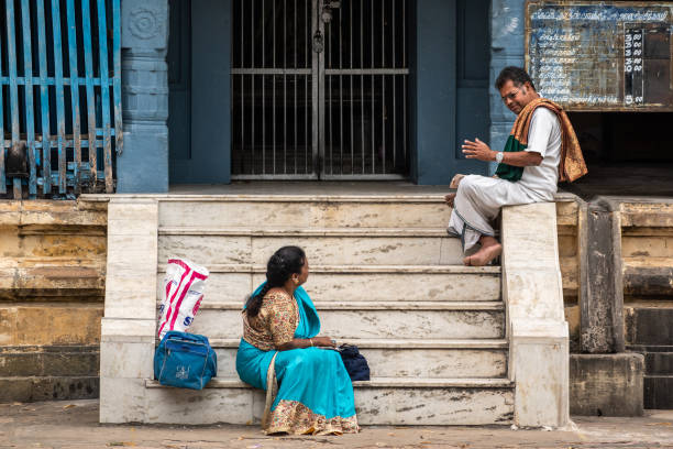 Sirkali, Tamil Nadu, India - February 2020: An Indian man and a woman having a conversation outside a shrine in an ancient Hindu temple in Sirkazhi.