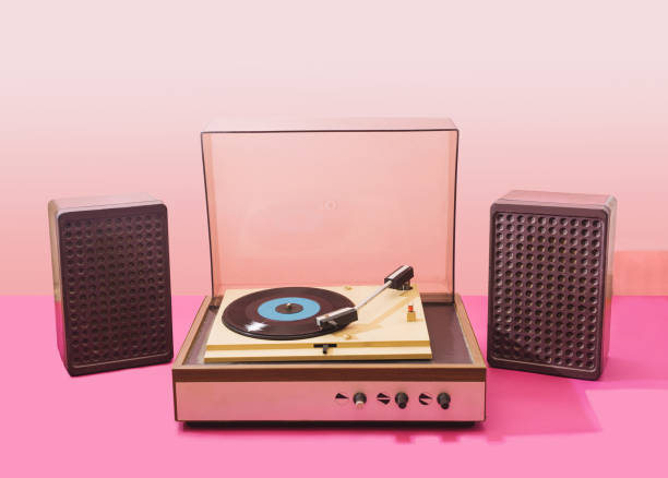Gramophone record player from sixties with speakers. Turntable for single vinyl with pink bottom with light pink background.