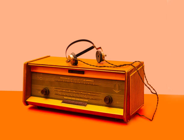 une radio antique avec vieux type d’écouteurs. arrangement d’ambiance rétro sur fond orange clair et orange clair. - radio haute fréquence photos et images de collection
