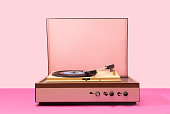 Gramophone record player from sixties. Turntable for single vinyl with pink bottom with light pink background.