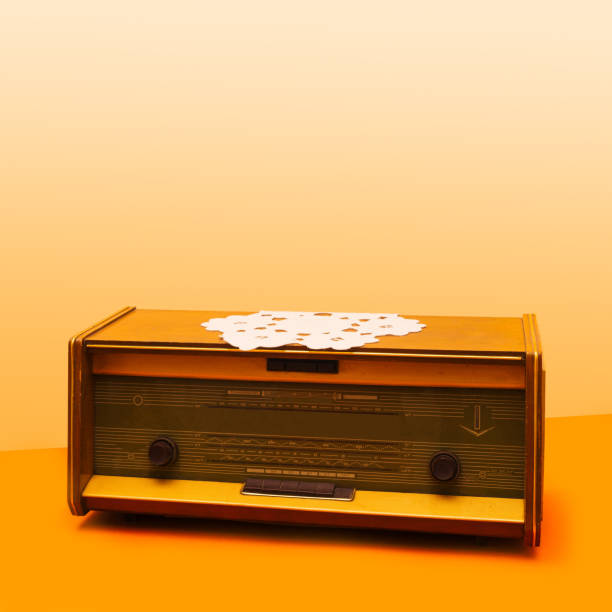 una radio antigua con mesa de tela de ganchillo vintage único en él. arreglo de la vieja escuela contra fondo beige y naranja claro. - radio old fashioned antique yellow fotografías e imágenes de stock