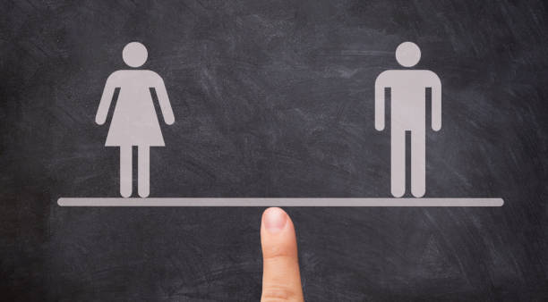 Male equals female, women equal men, Finger maintaining balance with a balance between man and woman on seesaw against a blackboard. Gender Equality Concept. Male equals female, women equal men, Finger maintaining balance with a balance between man and woman on seesaw against a blackboard. Gender Equality Concept. gender stereotypes stock pictures, royalty-free photos & images