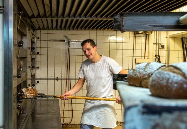 istock Baker taking bread out of oven 1334457165
