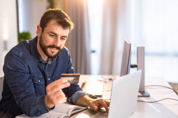 istock Young man working at home office and using a credit card to pay online. 1334459774