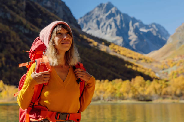 портрет туристки счастливой женщины на озере в осенних горах. горное озеро и туристическое - lake alaska mountain mountain range стоковые фото и изображения