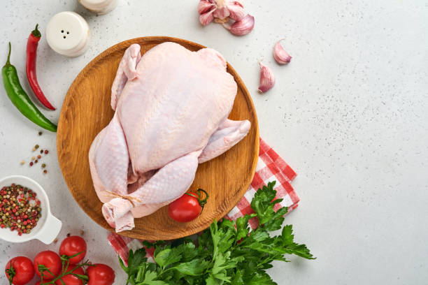 istock Whole raw chicken with ingredients for making rose pepper, lemon, thyme, garlic cherry tomato sorrel and salt in the kitchen on light grey slate stone or concrete background. Top view with copy space 1334463021