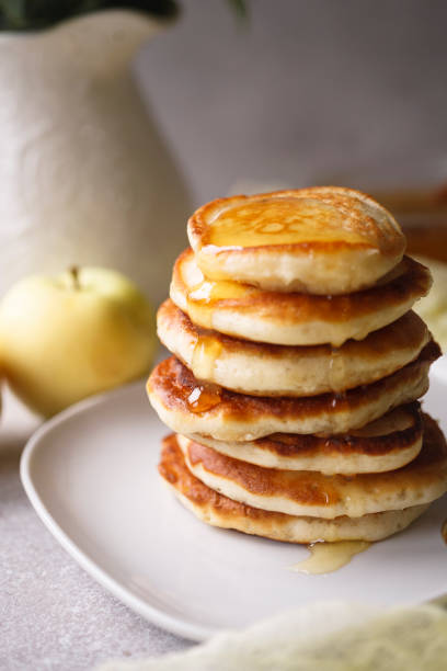 istock Stack of apple pancakes with pouring honey on white plate 1334463117