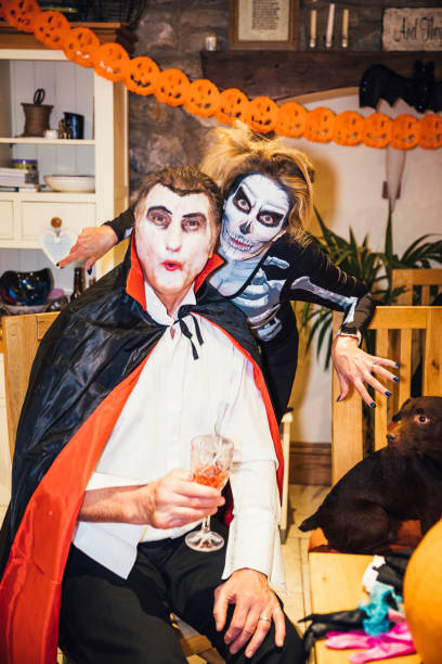 A group of five multi-ethnic men and women of mixed ages at a halloween party wearing costumes.
