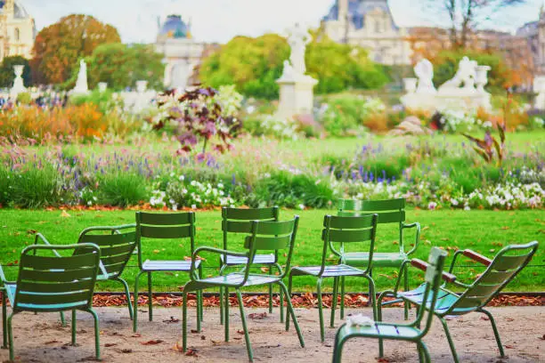 Traditional green chairs in the Tuileries garden in Paris on a bright, warm and sunny fall day