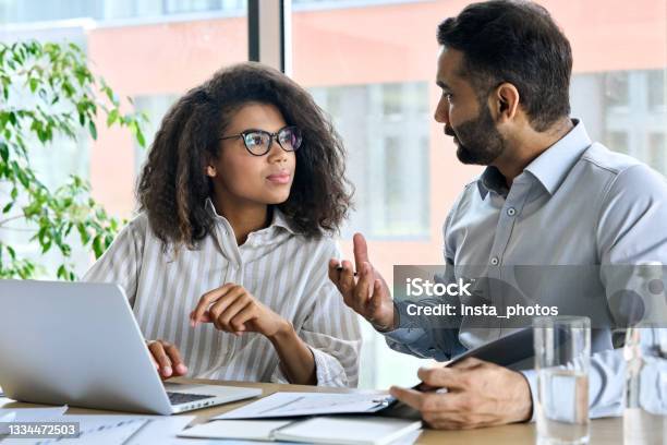 Indian Ceo Mentor Leader Talking To Female Trainee Using Laptop At Meeting Stock Photo - Download Image Now