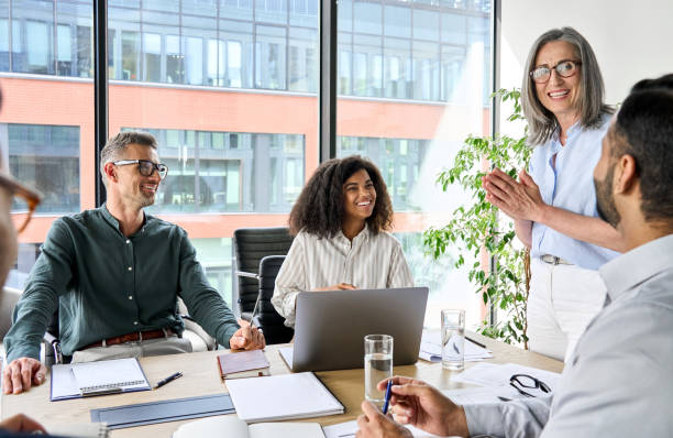 Happy diverse corporate team discussing project in boardroom office.