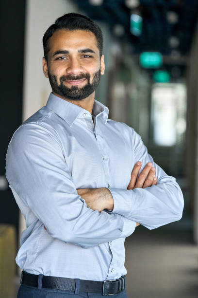 istock Smiling successful indian businessman looking at camera standing in office. 1334473020