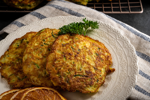 Zucchini pancakes: seasonal, homegrown healthy food. Garnished with parsley and dried orange slices.