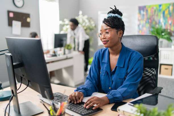 istock Polite, elegant customer service representative in large corporation sits at computer, tapping fingers on keyboard, surfing Internet, preparing documentation, filling out reports, making appointments 1334475203