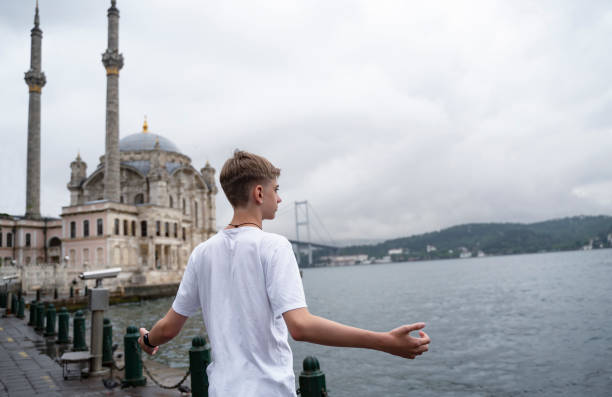 красивый подросток 15-18 лет стоит на берегу босфора, стамбула, турция, на естественном фоне мечети ортакой и босфорского моста. крупный план � - 13 14 years стоковые фото и изображения