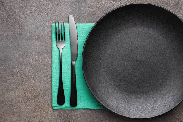 istock Black flatware and plate napkin top view 1334478792