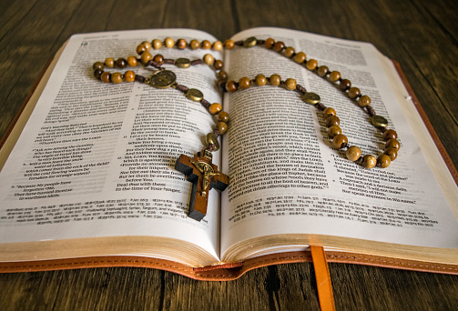 A rosary laying on an open Bible.