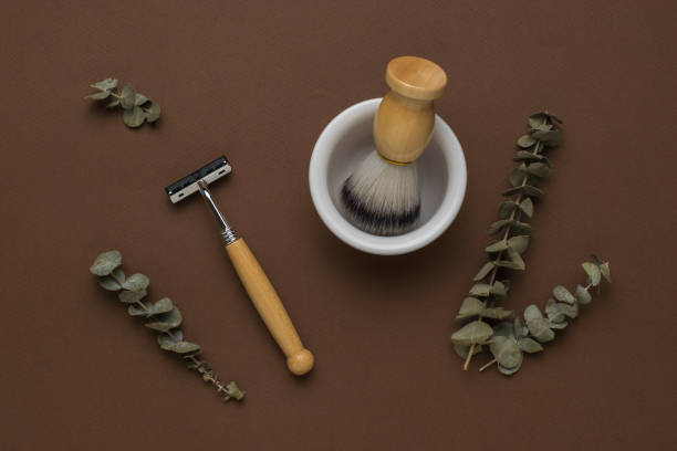 ユーカリのスプリグ、木製のカミソリ、茶色の背景にボウル付きのブラシ。フラットレイ。 - shaving equipment wash bowl bathroom razor ストックフォトと画像