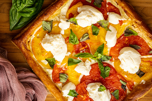 Roasted tomato tart on puff pastry: \n Homegrown red and yellow heirloom tomatoes are roasted on a crusted of puff pastry to form a fresh, healthy, and colorful vegetable tart. Finishing touches include dollops of ricotta cheese and torn basil leaves.