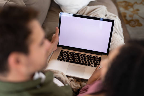 istock Happy diverse couple sitting on sofa in living room using laptop 1334483885