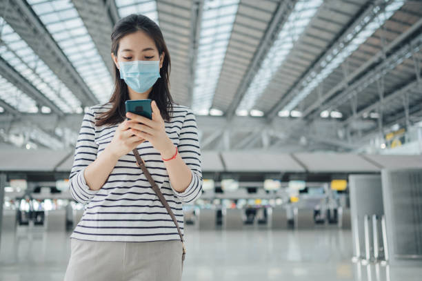 istock Asian women waiting for public train transportation subway using mobile wear facemask 1334484289