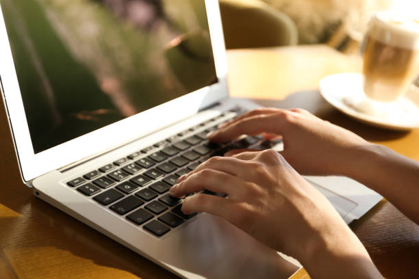 istock Woman using laptop at table, closeup of hands 1334485455
