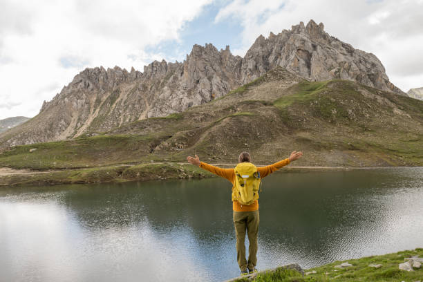 istock Hiker arms outstretched on alpine lake, peak view 1334486254