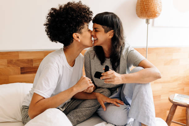 Couple celebrating their engagement at home Couple touching their noses together in their bedroom. Romantic young LGBTQ+ smiling cheerfully after getting engaged. Young lesbian couple celebrating their engagement at home. gay couple photos stock pictures, royalty-free photos & images