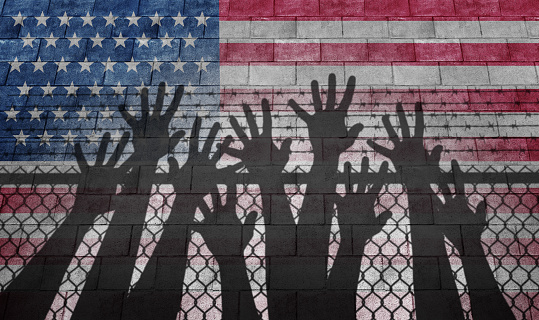 United States migrant crisis and US immigration or USA refugee concept as people on a border wall with an American flag as a social issue about illegal aliens or immigrants camp with 3D illustration elements.