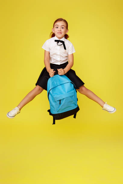 istock cute happy schoolgirl jumping up with backpack 1334491376