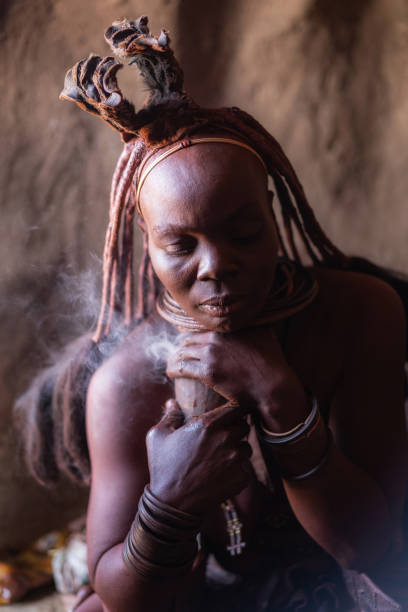 アフリカのナミビアの伝統的な村で小屋で煙風呂に入るヒンバの女性 - damaraland ストックフォトと画像