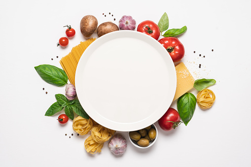 Italian cuisine white background with copy space. Traditional Mediterranean food. Vegetables, pasta, spices and herbs. Menu or recipe concept