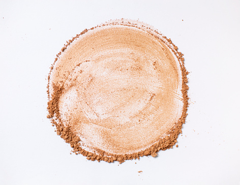 Bronze powder-highlighter cracked with brush stroke texture creates circle shape on a white background.