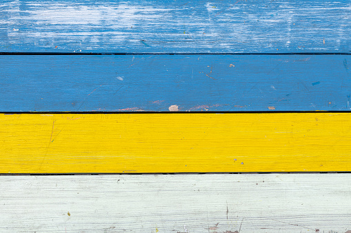 Abstract background of colored in blue, yellow and white paint old and grunge wooden planks with copy space