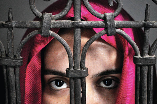 A woman behind a grid, her eyes watching the camera.
