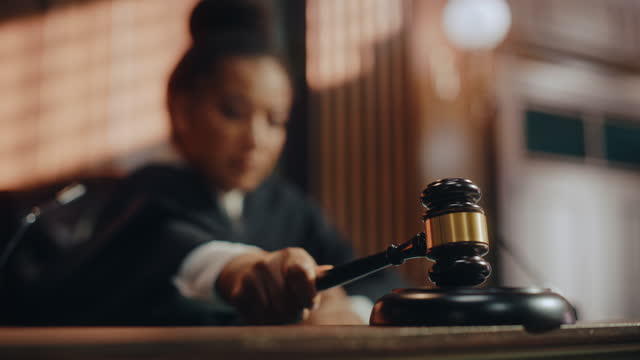 Court of Law Trial in Session: Portrait of Honorable Female Judge Reading Decision, striking Gavel. Presiding Justice Pronouncing Sentence. Innocent or Guilty Verdict. Cinematic Slow Motion Fade Out