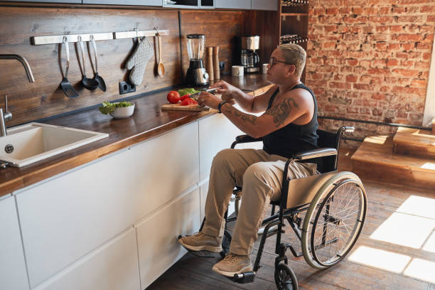 Woman in Wheelchair Cooking Full length portrait of contemporary tattooed woman with disability cooking dinner at home, copy space accessibility for persons with disabilities photos stock pictures, royalty-free photos & images