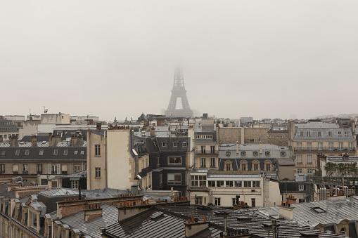 Fog and rain covering the Eiffel Tower in Paris, France.