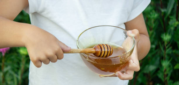 istock child eats honey in the garden. 1334509609