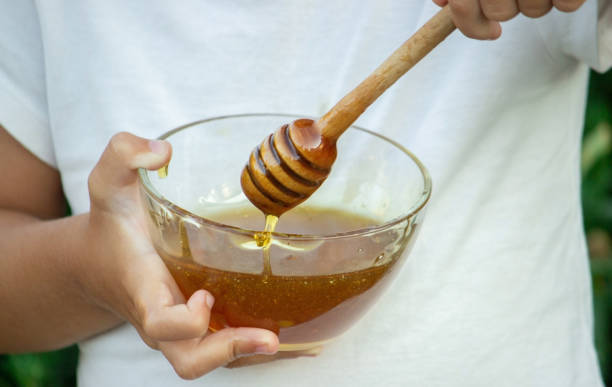 istock child eats honey in the garden. 1334509611