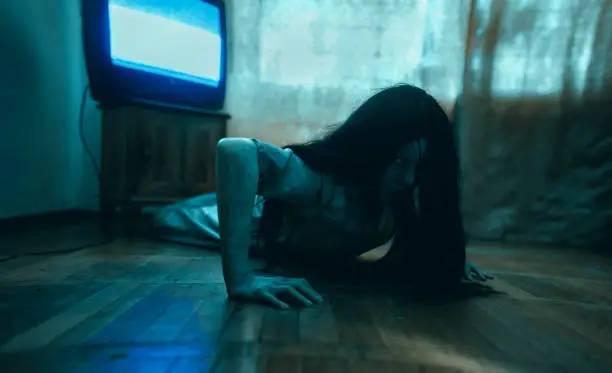 Photo of Girl in image of scary zombie crawls on floor in dark room.